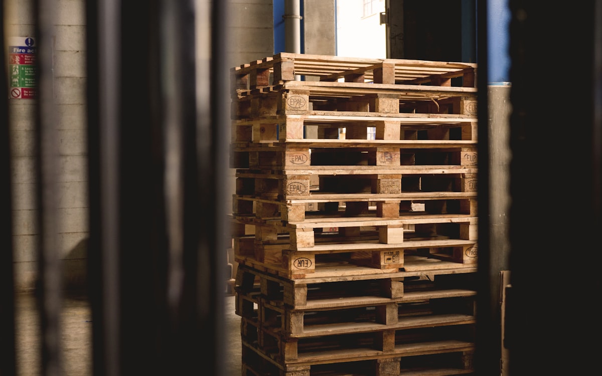 Interior de CEDIS con bins, cajas y tarimas en racks — tipos de embalaje primario, secundario y terciario